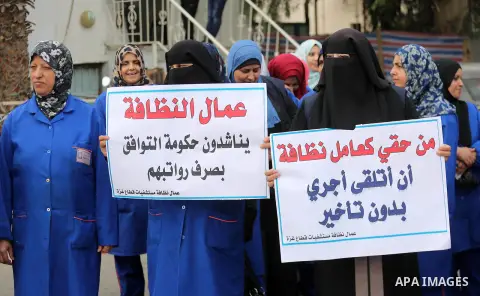 Palestinian cleaners hold banners during a protest to demand their salaries, in Gaza City December 20, 2017. Photo by Mohammed Asad