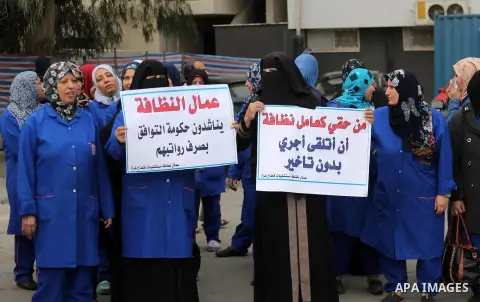 Palestinian cleaners hold banners during a protest to demand their salaries, in Gaza City December 20, 2017. Photo by Mohammed Asad