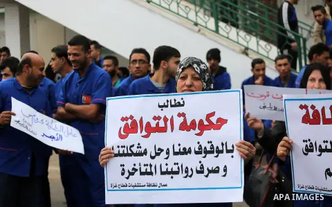 Palestinian cleaners hold banners during a protest to demand their salaries, in Gaza City December 20, 2017. Photo by Mohammed Asad