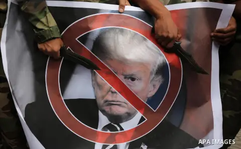Palestinian supporters of the Popular Front for the Liberation of Palestine (PFLP) burn posters depicting U.S. President Donald Trump, an Israeli flag and a U.S. flag during a protest against U.S. President Donald Trump'...