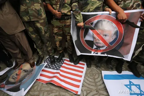 Palestinian supporters of the Popular Front for the Liberation of Palestine (PFLP) burn posters depicting U.S. President Donald Trump, an Israeli flag and a U.S. flag during a protest against U.S. President Donald Trump'...