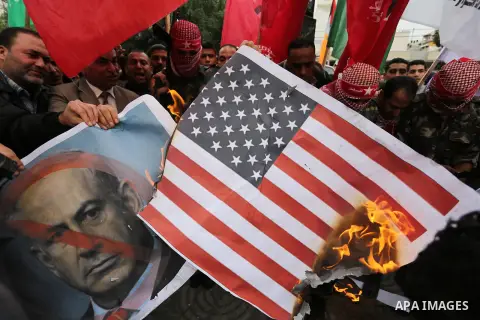Palestinian supporters of the Popular Front for the Liberation of Palestine (PFLP) burn posters depicting U.S. President Donald Trump, an Israeli flag and a U.S. flag during a protest against U.S. President Donald Trump'...