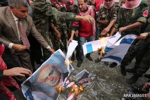 Palestinian supporters of the Popular Front for the Liberation of Palestine (PFLP) burn posters depicting U.S. President Donald Trump, an Israeli flag and a U.S. flag during a protest against U.S. President Donald Trump'...
