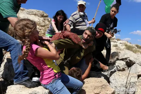 (FILES) This file photo taken on August 28, 2015 shows Palestinian Ahed Tamimi (L) fighting with other members of her family to free a Palestinian boy (bottom) held by an Israeli soldier (C) during clashes between Israel...