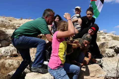 (FILES) This file photo taken on August 28, 2015 shows Palestinian Ahed Tamimi (L) fighting with other members of her family to free a Palestinian boy (bottom) held by an Israeli soldier (C) during clashes between Israel...