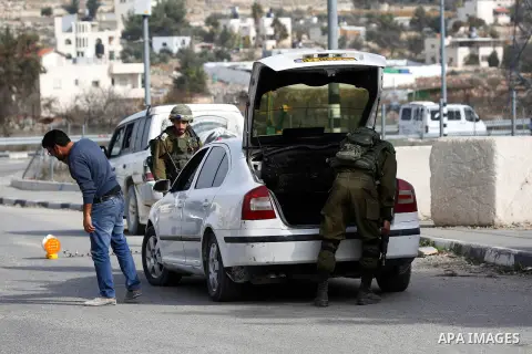 Israeli soldiers check the ID of Palestinian drivers as they inspect a vehicle at a checkpoint in the West Bank city of Hebron, on December 23, 2017. Photo by Wisam Hashlamoun
