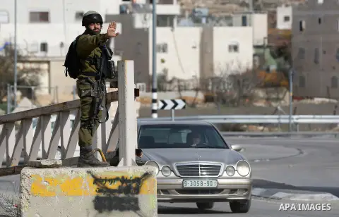 Israeli soldiers check the ID of Palestinian drivers as they inspect a vehicle at a checkpoint in the West Bank city of Hebron, on December 23, 2017. Photo by Wisam Hashlamoun