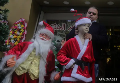 A Palestinian shop keeper dresses plastic models outfitted as Santa Claus (or Father Christmas) outside his shop in Gaza City on December 25, 2017. Photo by Mohammed Dahman