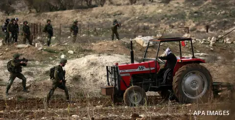 An elderly Palestinian farmer rides his tractor during clashes between Palestinian protesters and Israeli security forces near the Huwwara checkpoint, near the West Bank city of Nablus on December 27, 2017. Photo by Shad...