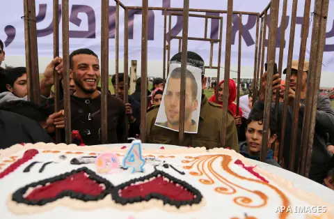 A Palestinian man playing the role of Israeli soldier Oron Shaul is seen in a mock jail as he tries to participate in a birthday party, during a rally in solidarity with Palestinian prisoners held in Israeli jails, in th...