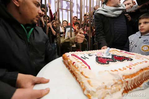 A Palestinian man playing the role of Israeli soldier Oron Shaul is seen in a mock jail as he tries to participate in a birthday party, during a rally in solidarity with Palestinian prisoners held in Israeli jails, in th...