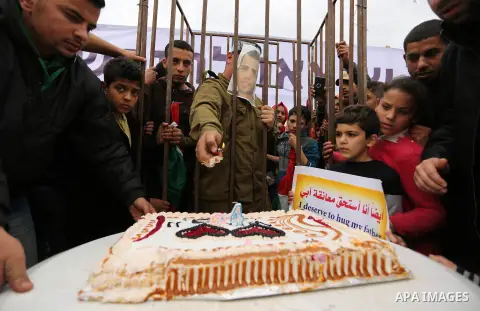 A Palestinian man playing the role of Israeli soldier Oron Shaul is seen in a mock jail as he tries to participate in a birthday party, during a rally in solidarity with Palestinian prisoners held in Israeli jails, in th...