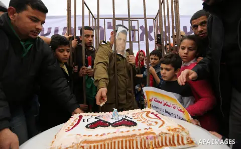 A Palestinian man playing the role of Israeli soldier Oron Shaul is seen in a mock jail as he tries to participate in a birthday party, during a rally in solidarity with Palestinian prisoners held in Israeli jails, in th...