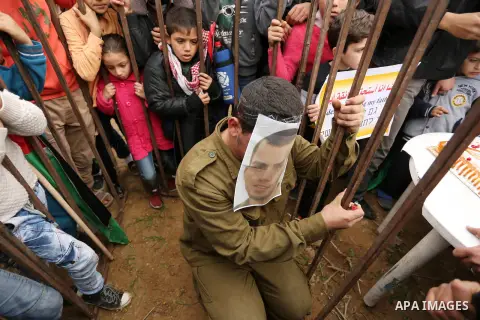 A Palestinian man playing the role of Israeli soldier Oron Shaul is seen in a mock jail as he tries to participate in a birthday party, during a rally in solidarity with Palestinian prisoners held in Israeli jails, in th...