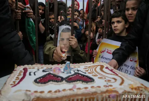 A Palestinian man playing the role of Israeli soldier Oron Shaul is seen in a mock jail as he tries to participate in a birthday party, during a rally in solidarity with Palestinian prisoners held in Israeli jails, in th...