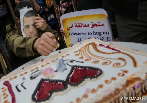 A Palestinian man playing the role of Israeli soldier Oron Shaul is seen in a mock jail as he tries to participate in a birthday party, during a rally in solidarity with Palestinian prisoners held in Israeli jails, in th...