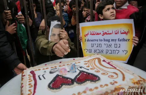 A Palestinian man playing the role of Israeli soldier Oron Shaul is seen in a mock jail as he tries to participate in a birthday party, during a rally in solidarity with Palestinian prisoners held in Israeli jails, in th...