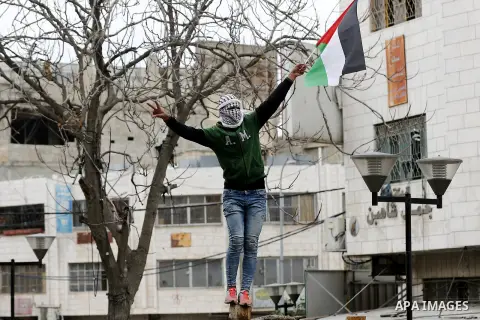 A Palestinian demonstrator waves his country's national flag during clashes with Israeli security forces in the occupied West Bank city of Hebron on December 29, 2017 as protests continue over US President Donald Trump's...