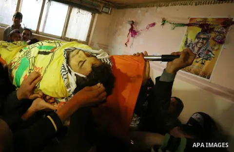 Mourners carry the body of Palestinian Jamal Mesleh, 21, who died of his injuries during clashes with Israeli security forces on Friday, during his funeral in the al-Maghazi refugee camp in the central Gaza Strip Decembe...