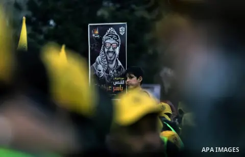 Supporters of the Fatah movement hold up a portrait of late Palestinian leader Yasser Arafat during a rally in Gaza City on December 31, 2017, marking the 53rd anniversary of the creation of the political party. Photo by...