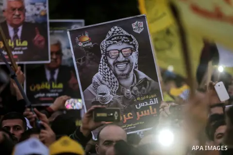 Supporters of the Fatah movement hold up a portrait of late Palestinian leader Yasser Arafat during a rally in Gaza City on December 31, 2017, marking the 53rd anniversary of the creation of the political party. Photo by...