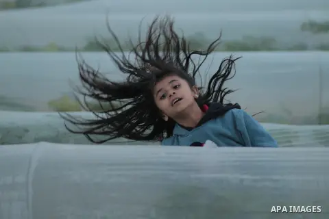 A girl with wind blowing hair at greenhouses. Photo by Sanad Ltefa