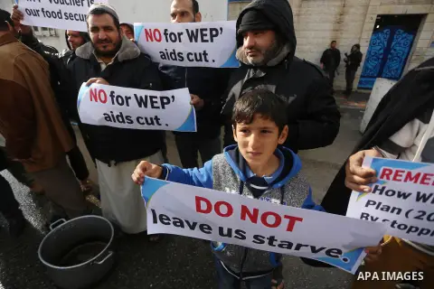 Palestinians hold banners during a protest against aid cut, in front of United Nations Development Programme office (UNDP), in Gaza City January 17, 2018. Photo by Mohammed Asad