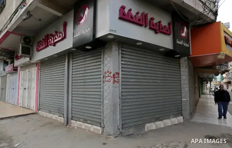 A Palestinian walks past closed shops during a commercial strike in protest against the economic situation, in Gaza city on January 23, 2018. Photo by Ashraf Amra