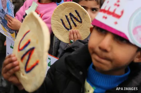 Palestinian children hold bread patties during a protest against aid cuts, outside the United Nations' offices in Khan Yunis in the southern Gaza Strip on January 28, 2018. On January 16, Washington held back $65 million...