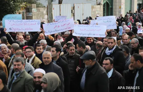 Palestinian employee of United Nations Relief and Works Agency (UNRWA) hold a sign during a protest against a U.S. decision to cut aid, in Gaza City January 29, 2018. Photo by Ashraf Amra