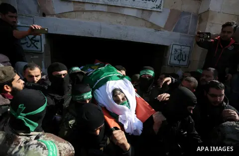 Palestinian militants from the Ezzedine al-Qassam Brigades, the armed wing of the Hamas movement carry the body of Hamas senior leader Imad al-Alami during his funeral outside the al-Omari mosque in Gaza City on January...