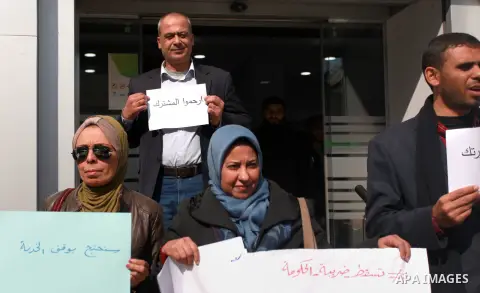 Palestinians hold banners during a protest against Jawwal's decision to add 16% VAT to its customers in the Gaza Strip in Gaza city on January 31, 2018. Photo by Mahmoud Ajour