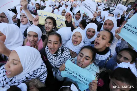 Palestinian school students shout slogans and hold placards in a protest against the US move to freeze funding for the UN agency for Palestinian refugees on January 31, 2018 at the al-Nusairat refugee camp, in central Ga...