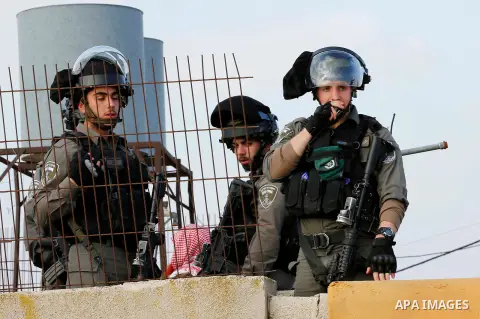 Israeli soldiers stand guard while Israeli workers dismantle a Palestinian structure in the West Bank village of Yatta, near Hebron January 31, 2018. Photo by Wisam Hashlamoun
