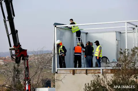 Israeli workers guarded by Israeli soldiers dismantle a Palestinian structure in the West Bank village of Yatta, near Hebron January 31, 2018. Photo by Wisam Hashlamoun