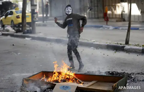 A masked Palestinian protester uses a slingshot to hurl stones towards Israeli security forces during clashes in the West Bank city of Hebron on February 2, 2018 2018 as demonstrations continue over the US president's co...