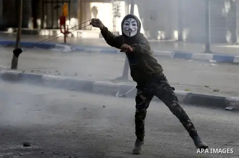 A masked Palestinian protester uses a slingshot to hurl stones towards Israeli security forces during clashes in the West Bank city of Hebron on February 2, 2018 2018 as demonstrations continue over the US president's co...