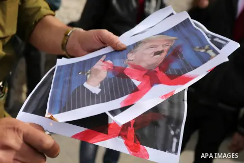 A Palestinian demonstrator burns posters of U.S. President Donald Trump during a protest to show solidarity with Palestinian prisoners held in Israeli jails, in front of Red cross office in Gaza city on February 5, 2018....
