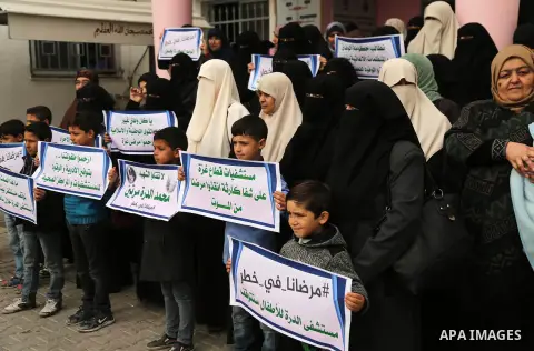 Palestinians hold placards during a protest outside Durra hospital in Gaza City after it stopped its services on February 7, 2018 after it ran out of fuel. Seven medical centers in Gaza have stopped services due to lack...
