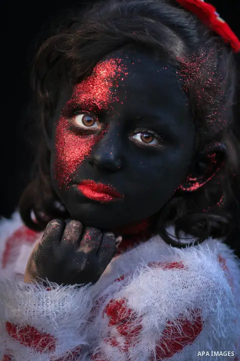 Cropped portrait of a girl with black red colored face. Photo by Sanad Ltefa