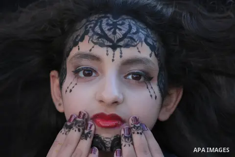 Cropped portrait of a girl with red lipstick, and a black paint on her face putting fingers near face. Photo by Sanad Ltefa