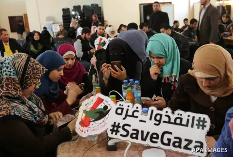 Palestinians tweet with the hashtag "#SaveGaza" against the siege on the Gaza Strip, in Gaza city, on February 14, 2018. Photo by Ashraf Amra