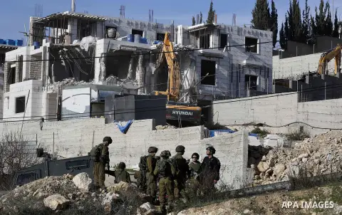 Israeli border police officers stand guard as Israeli machineries demolish an under-construction Palestinian residential building near Hebron, in the occupied West Bank February 14, 2018. Photo by Wisam Hashlamoun
