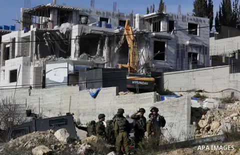 Israeli border police officers stand guard as Israeli machineries demolish an under-construction Palestinian residential building near Hebron, in the occupied West Bank February 14, 2018. Photo by Wisam Hashlamoun