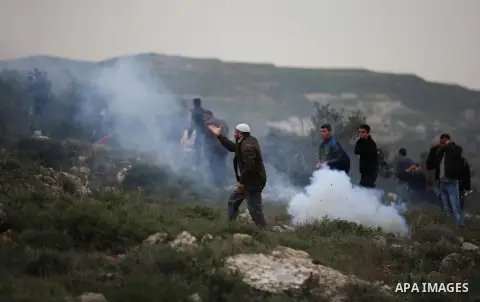 Palestinian protesters stand in a cloud of tear gas fired by Israeli troops during clashes at the Beta village near the West Bank city of Nablus, 15 February 2018. According to local sources at least five Palestinian wer...