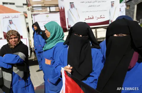 Palestinian cleaners in al-Shifa hospital hold Qatari flags and placards to demand thier salaries during a press conference of Qatar's Ambassador to the Palestinian Authority, Mohammed Al Emadi in Gaza city on February 1...