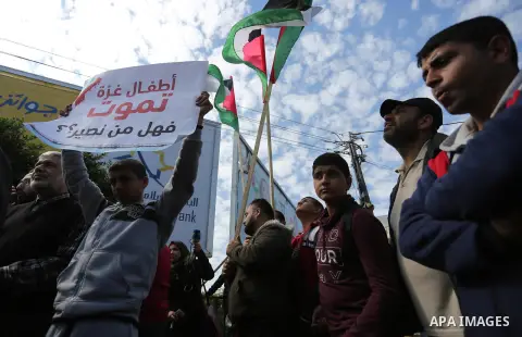 Palestinians hold banners in Gaza City on February 20, 2018 during a general strike to protest the humanitarian situation in Gaza. Photo by Ashraf Amra