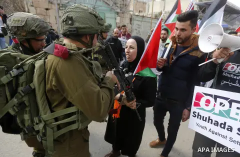 Palestinian protesters hold placards during a demonstration against the closure of Shuhada street, on the 24th anniversary of the closure, on February 23, 2018 in the West Bank city of Hebron. On February 25, 1994 Israel...