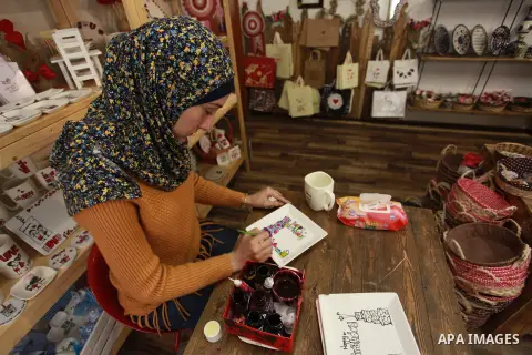 A Palestinian artist Dima Sha'sha'a "owner of Tezzkar Project" works at her shop in Gaza city on February 28, 2018. Dima and her brother Hamdi take the drawing on dishes, cardboard and glass as a job for nearly seven yea...