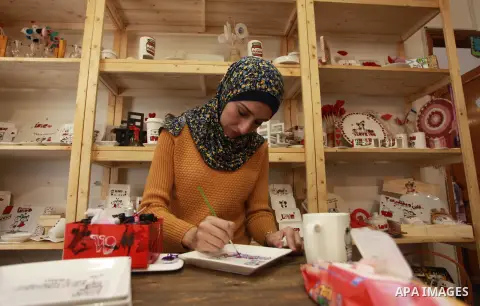 A Palestinian artist Dima Sha'sha'a "owner of Tezzkar Project" works at her shop in Gaza city on February 28, 2018. Dima and her brother Hamdi take the drawing on dishes, cardboard and glass as a job for nearly seven yea...